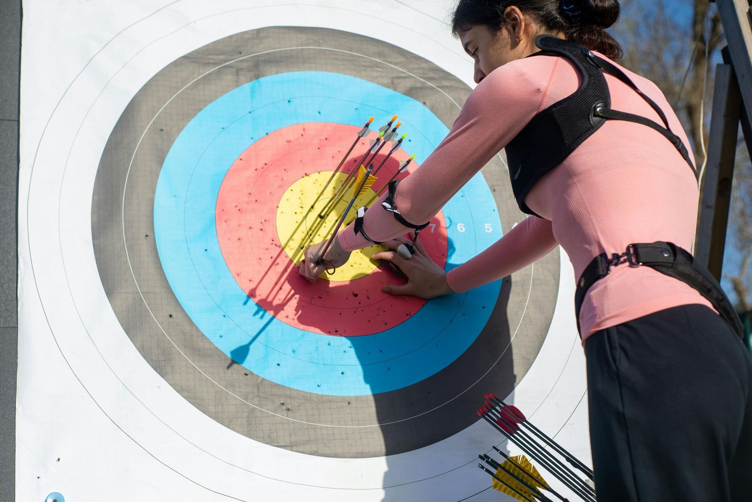 Woman Pulling Arrows from Archery Target Board