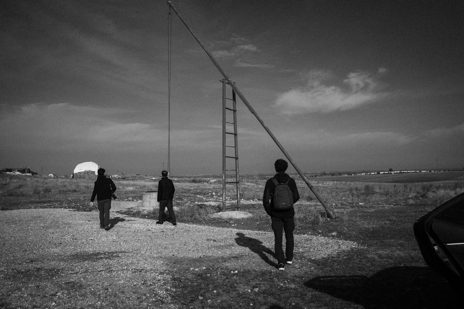 Black and white photo of people standing near a pole