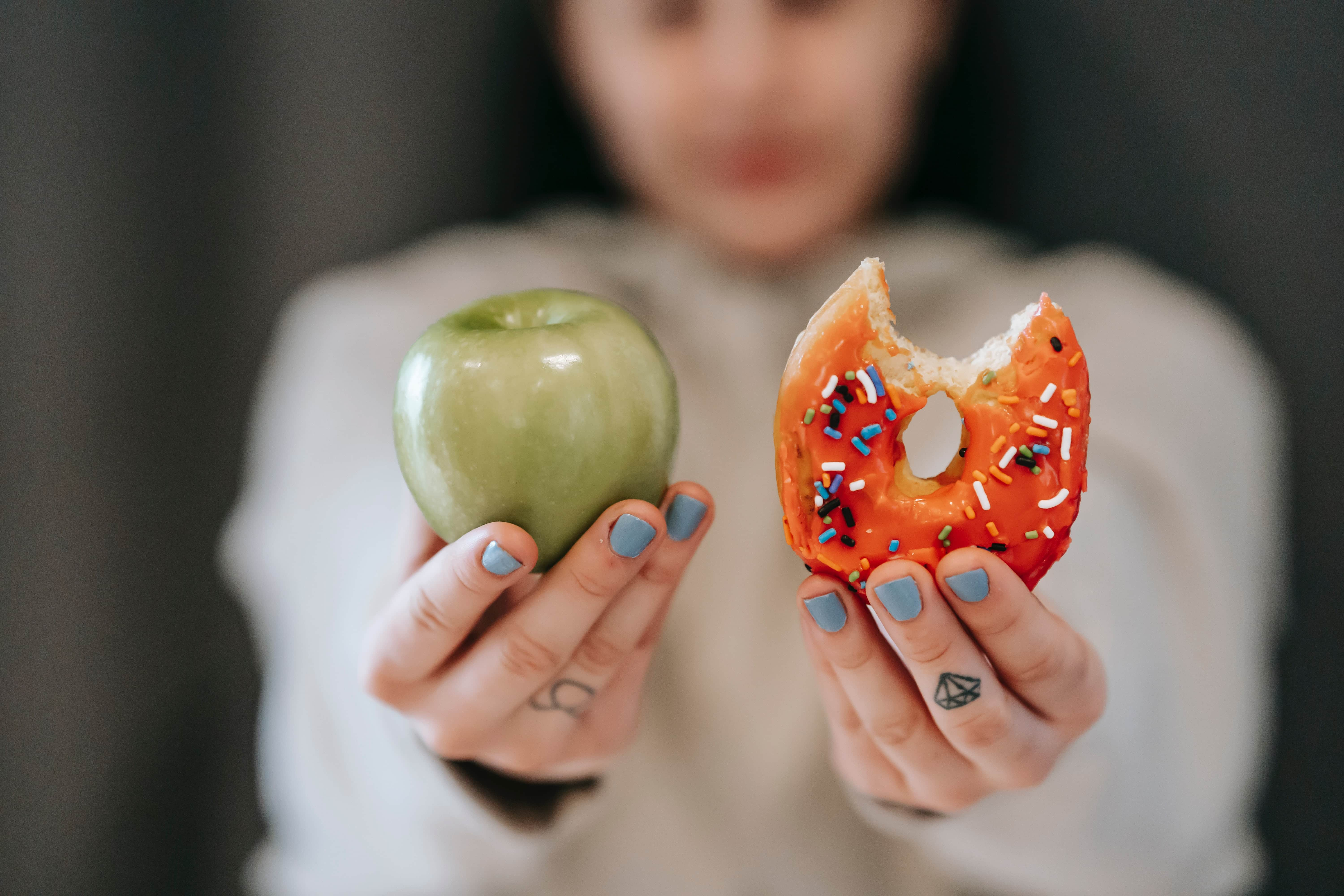 woman choosing between apple and donut