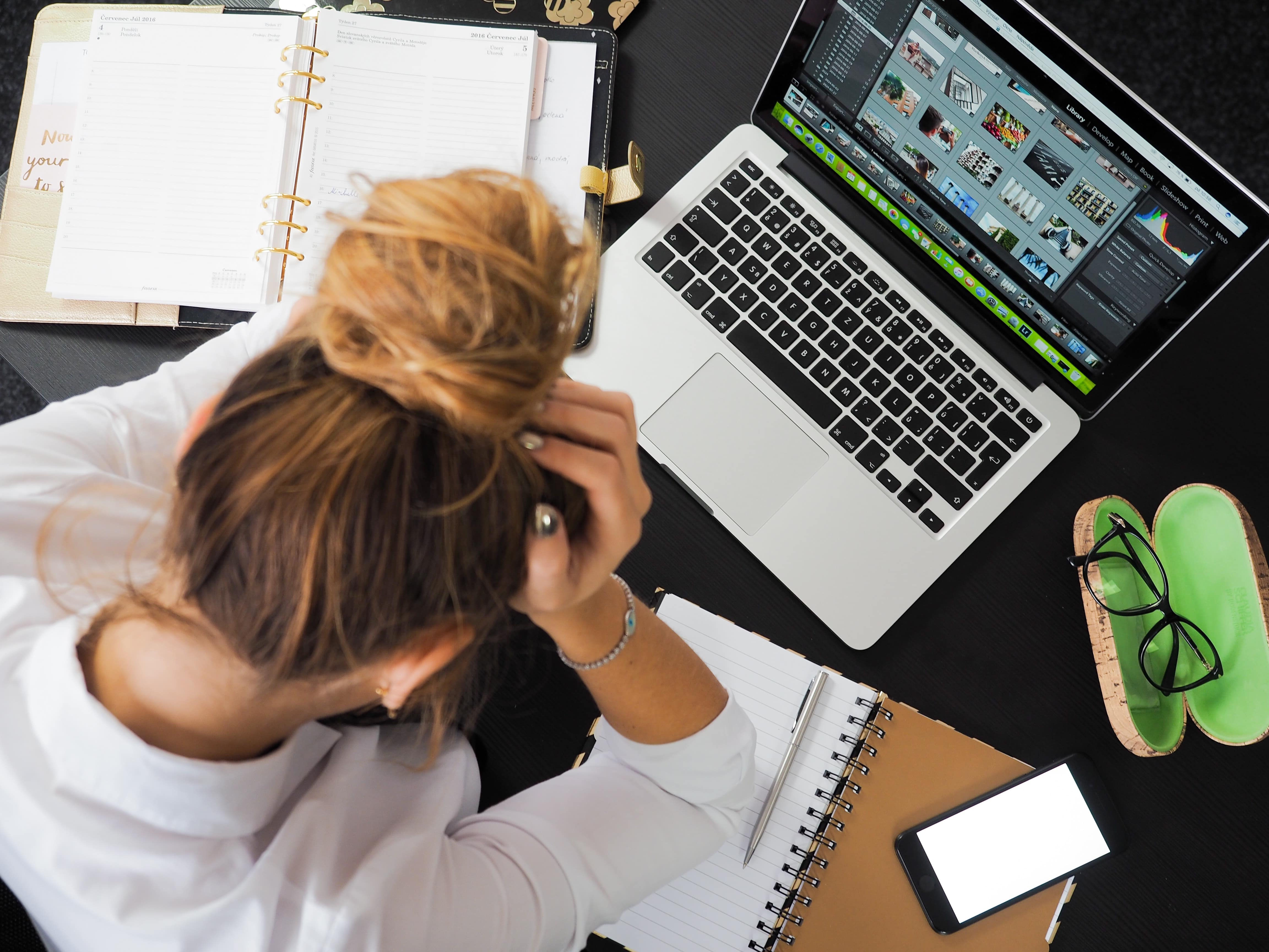 woman stressed in front of laptop and notepad