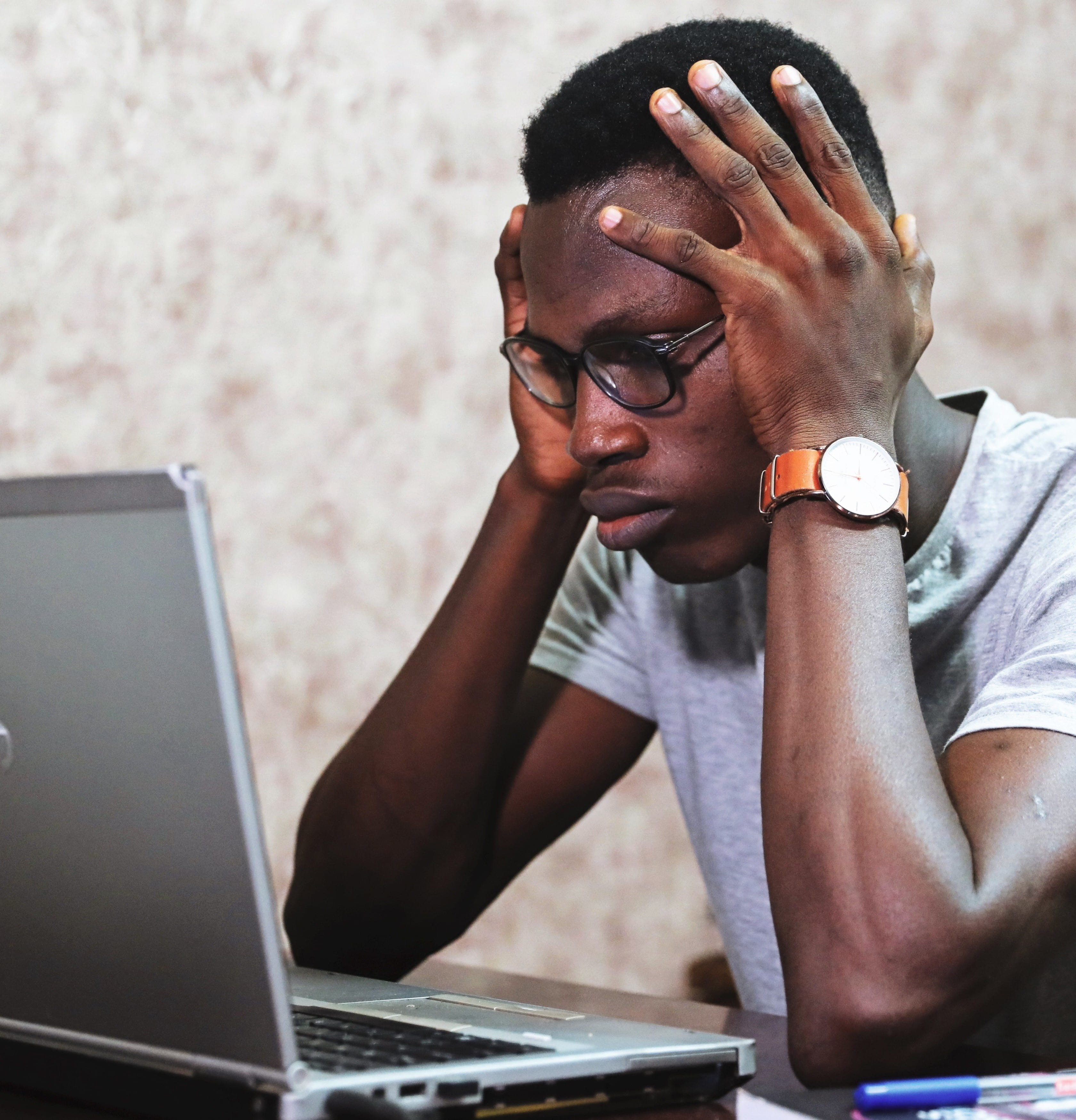 Man looking at laptop holding his head in stress